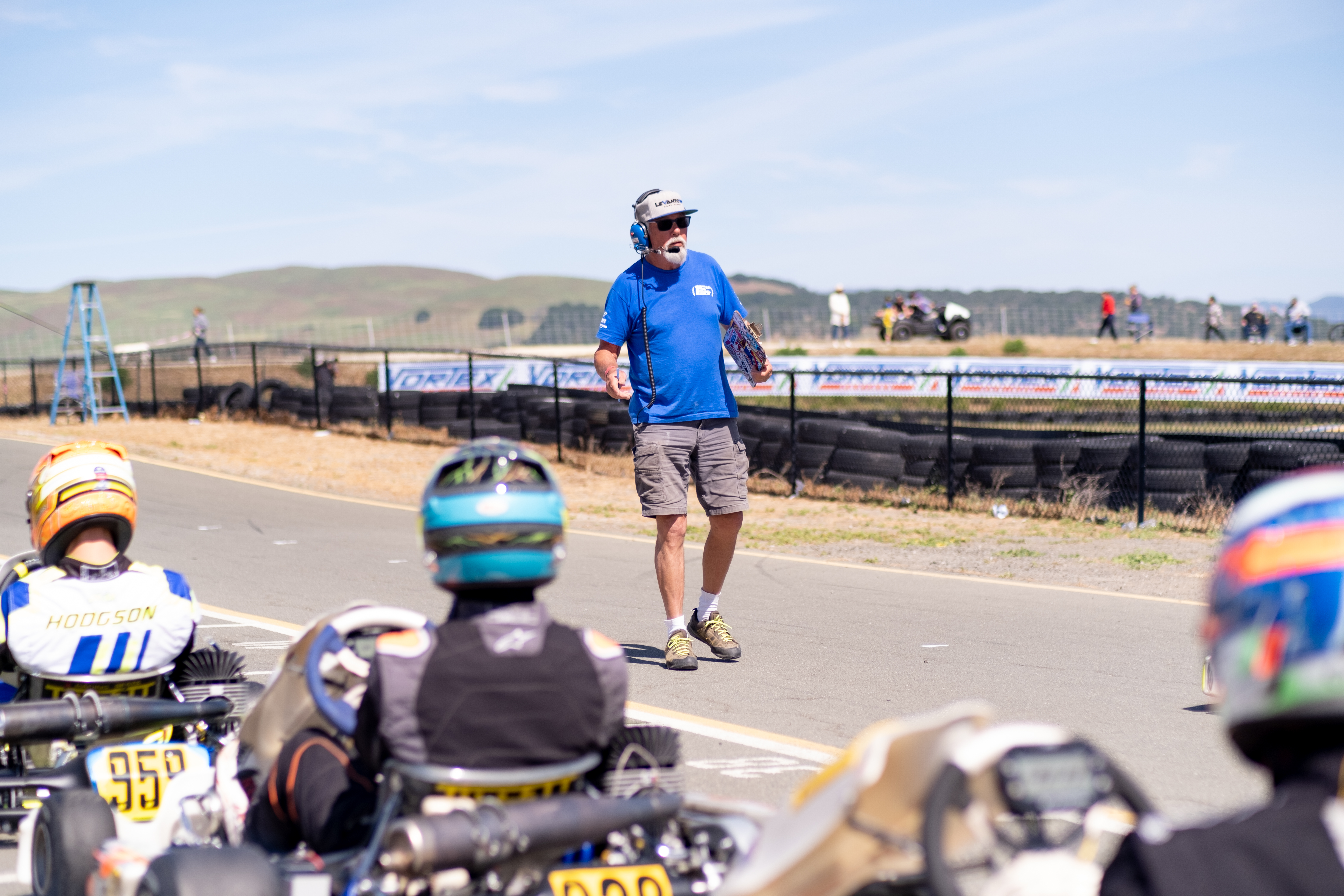 An instructor addressing helmeted drivers viewed from behind at Sonoma Raceway